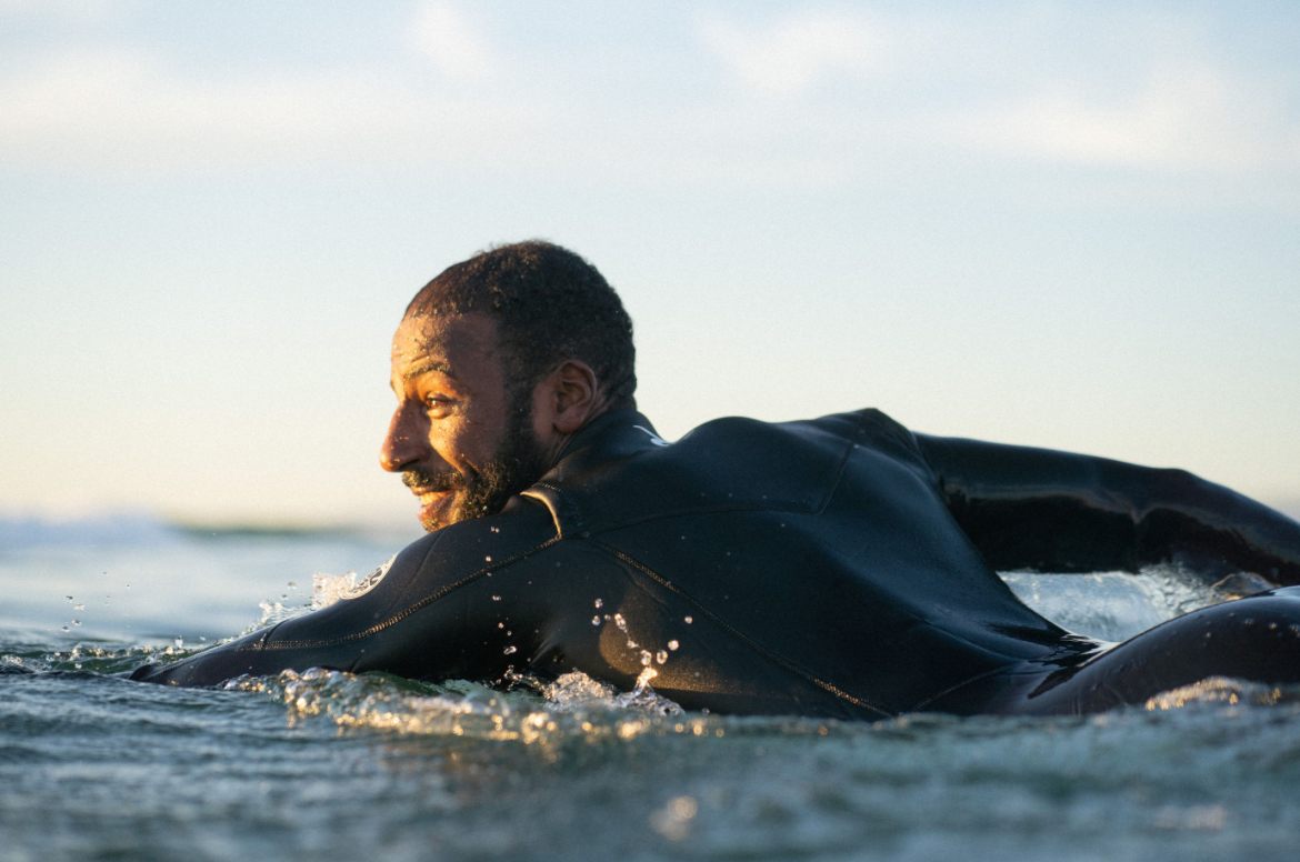 Momo, founder of NAVA Surf Adventure, in the ocean at sunset