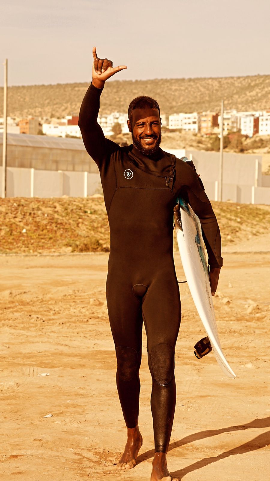 Momo holding his surfboard, smiling