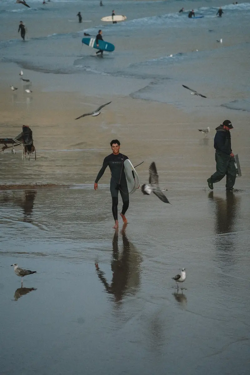 Reda, surf coach at NAVA, walking out of the water with his board