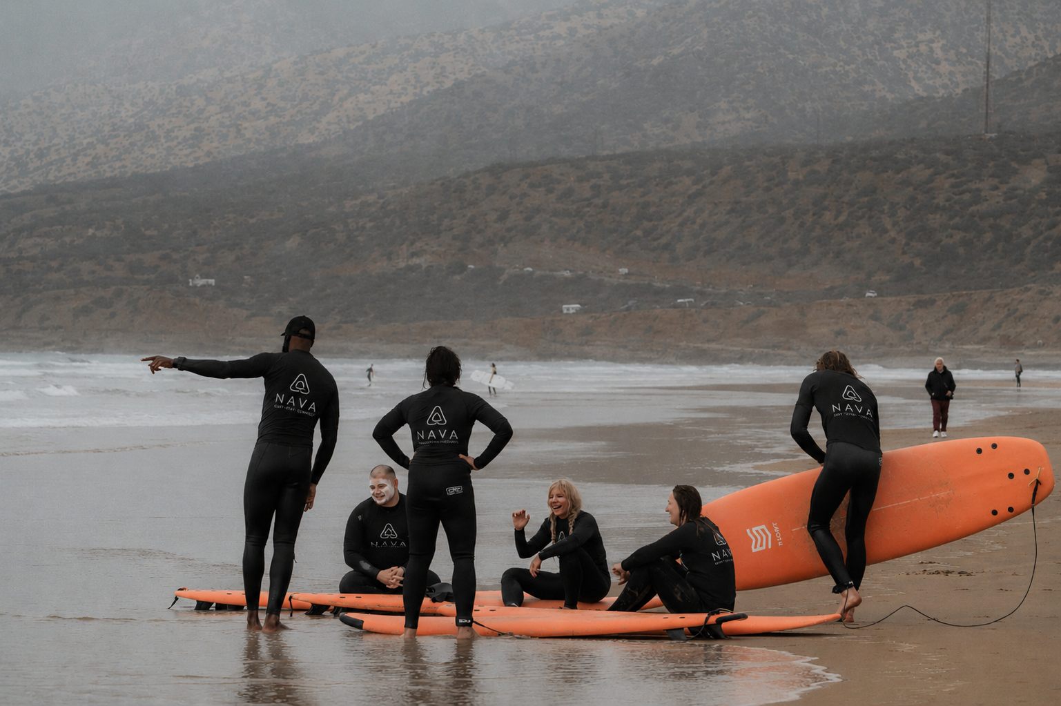 NAVA coach briefing a group of surfers on the beach